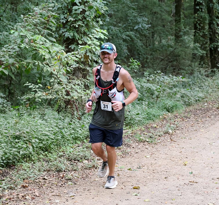 Cody racing solo on a wooded trail during an ultramarathon
