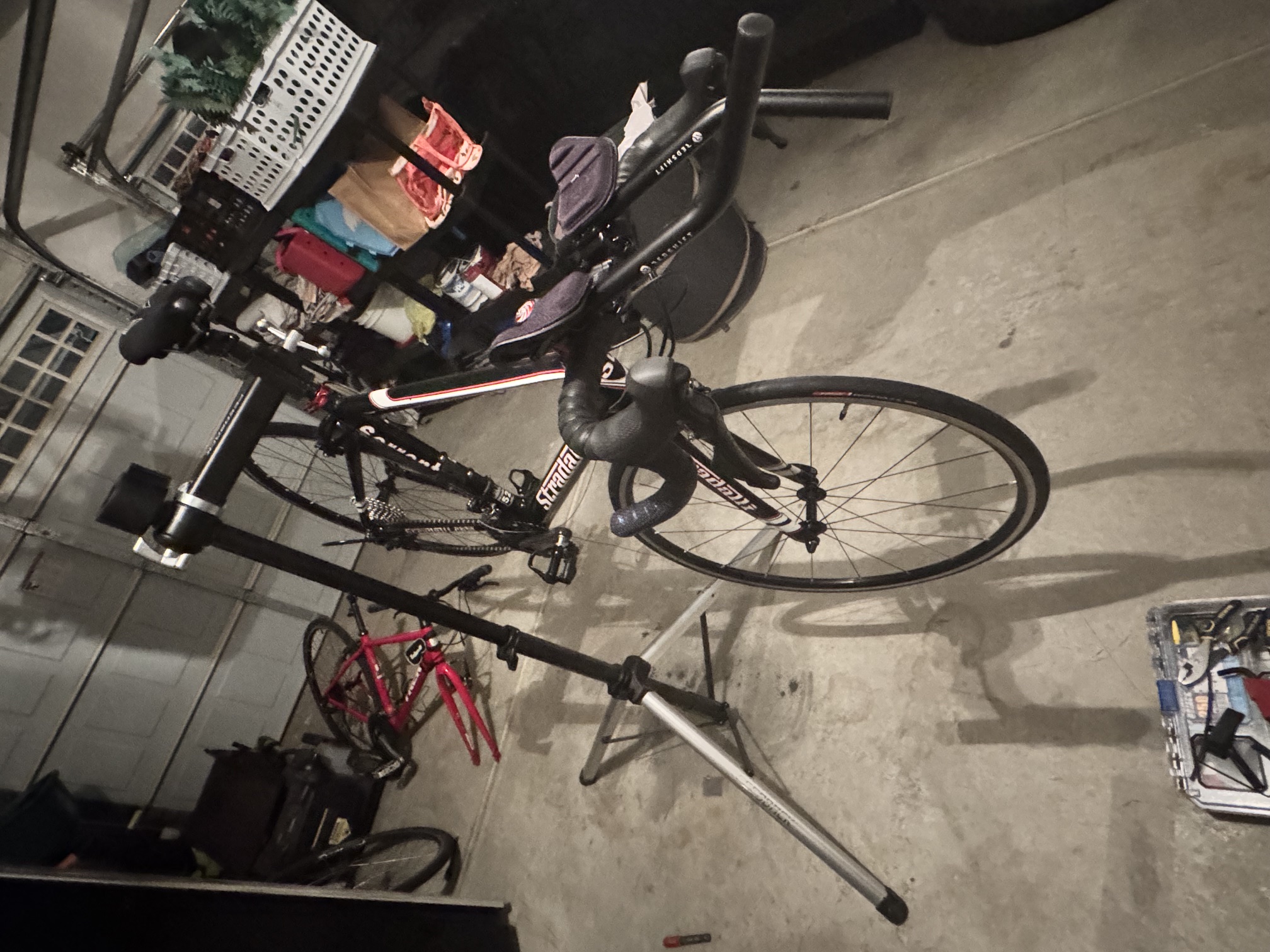The Stradalli Sorrento on the Feedback Sports repair stand in the garage, fully assembled with wrapped cockpit, aerobars, and complete drivetrain.
